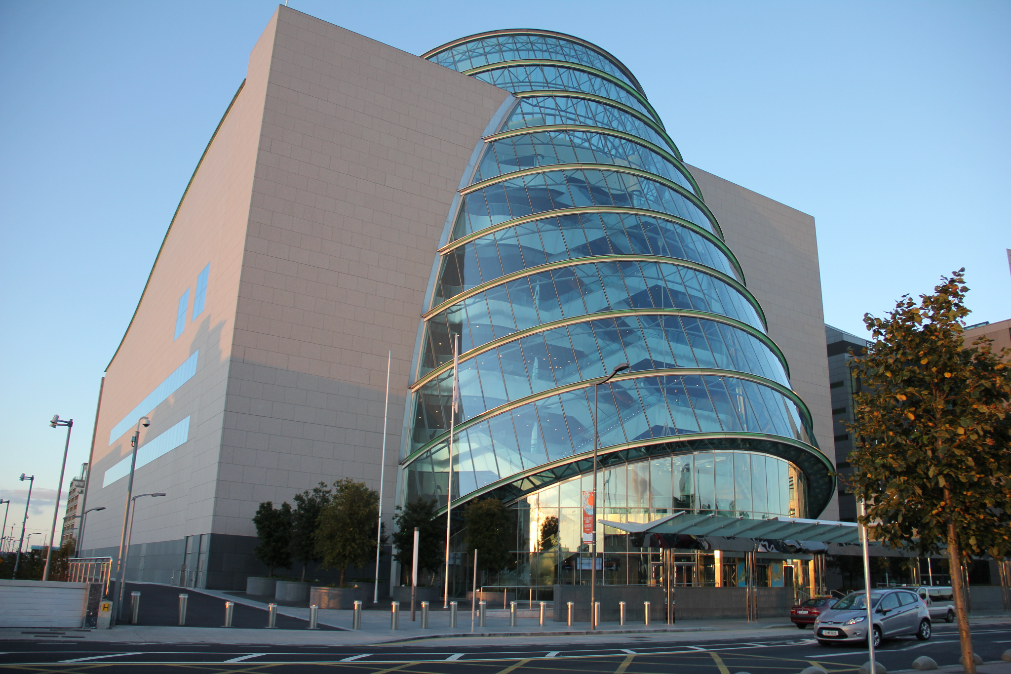 Photograph of the Convention Centre Dublin. It is a large glass cylindrical building, tilted and set into a brick cube.