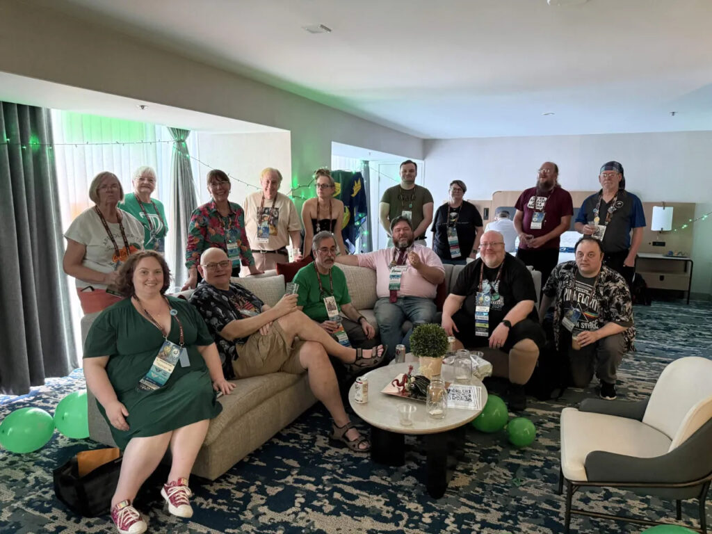 A group of 15 people in a room decorated with green. 