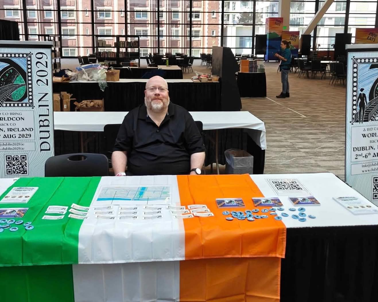 One of our co-chairs at a Fan Table in Seattle in 2025. The Irish flag is draped across the table and is covered in freebies.