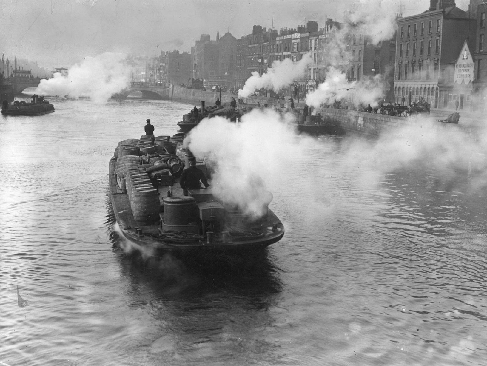 A smokey barge carrying barrels of beer on the river Liffey.