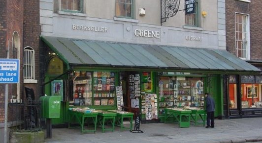 Photo of a bookshop with awnings and book-barrows out in front. The name 'Greene' is embossed on the front.