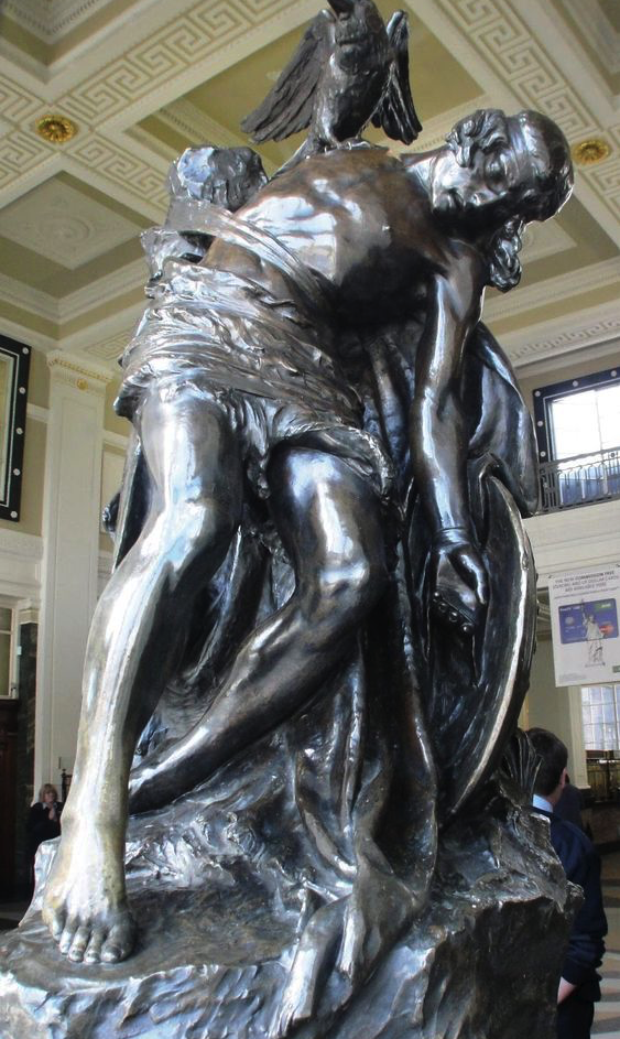 A bronze statue of a barefoot warrior tied to a man-sized rock by his belt. A raven sits on his shoulder.